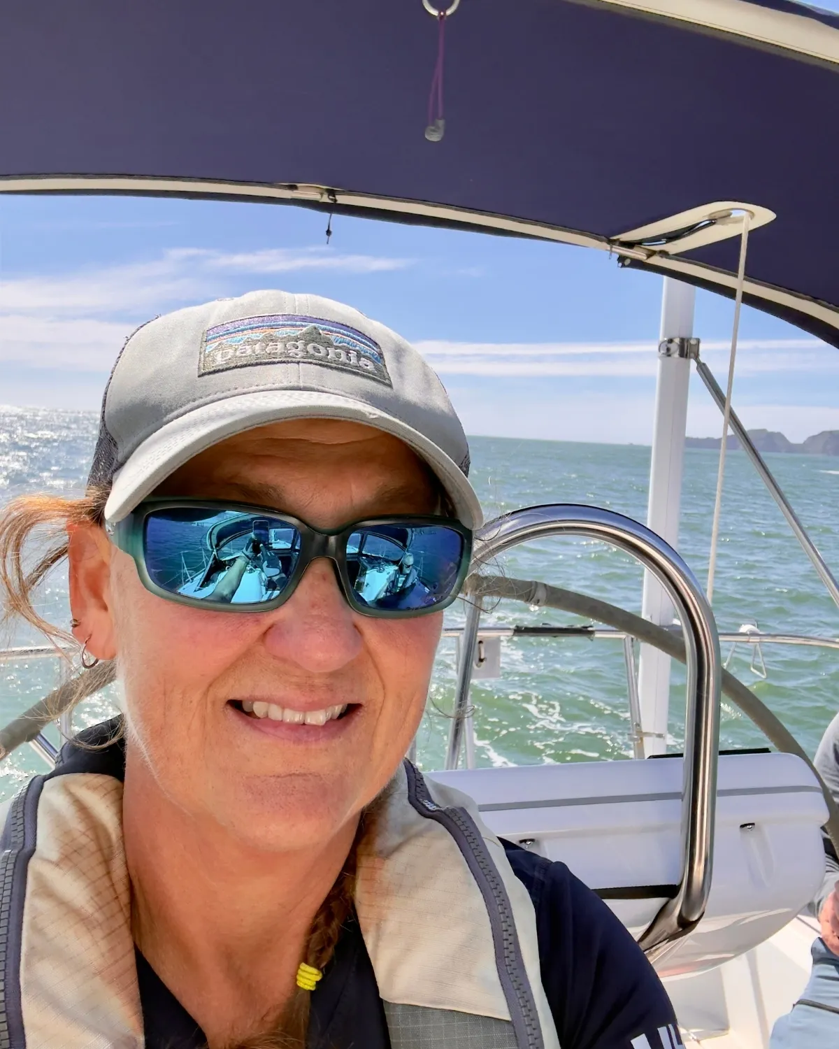 Captain Andrea smiling at the helm of a sailboat on San Francisco Bay